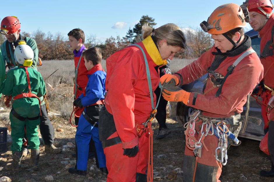 Team preparing for a speleology expedition outdoors with helmets and harnesses.