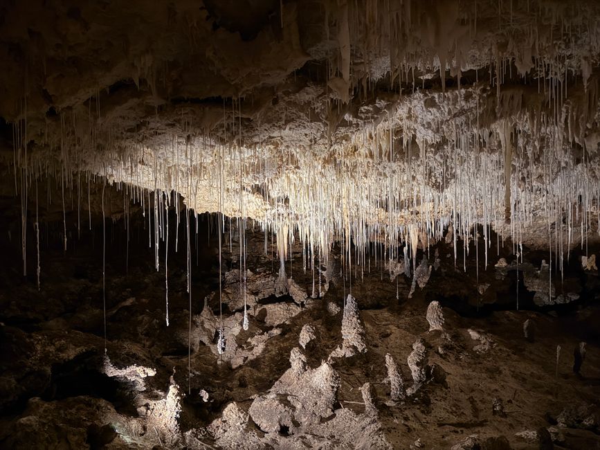Dramatic view of stalactites hanging from a cave ceiling, casting shadows.